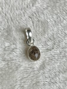 In deze kleine zilveren hanger en as is 6 bij 4 mm groot en de as is tot een soort steen gemaakt.