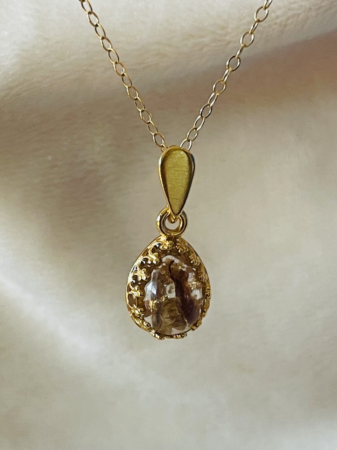 Deze hanger het 'navelstrengeltje', heeft stukje navelstreng met gouden vlokjes verwerkt in de steen.